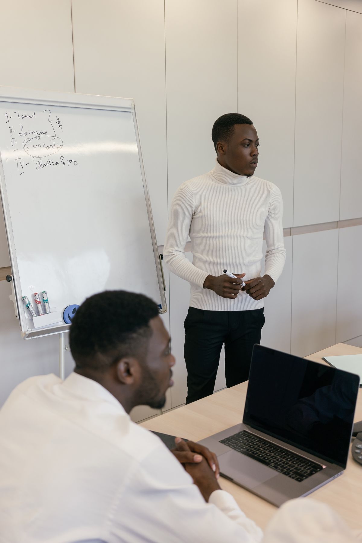 African professionals using a whiteboard and laptop to redesign an end-to-end business process